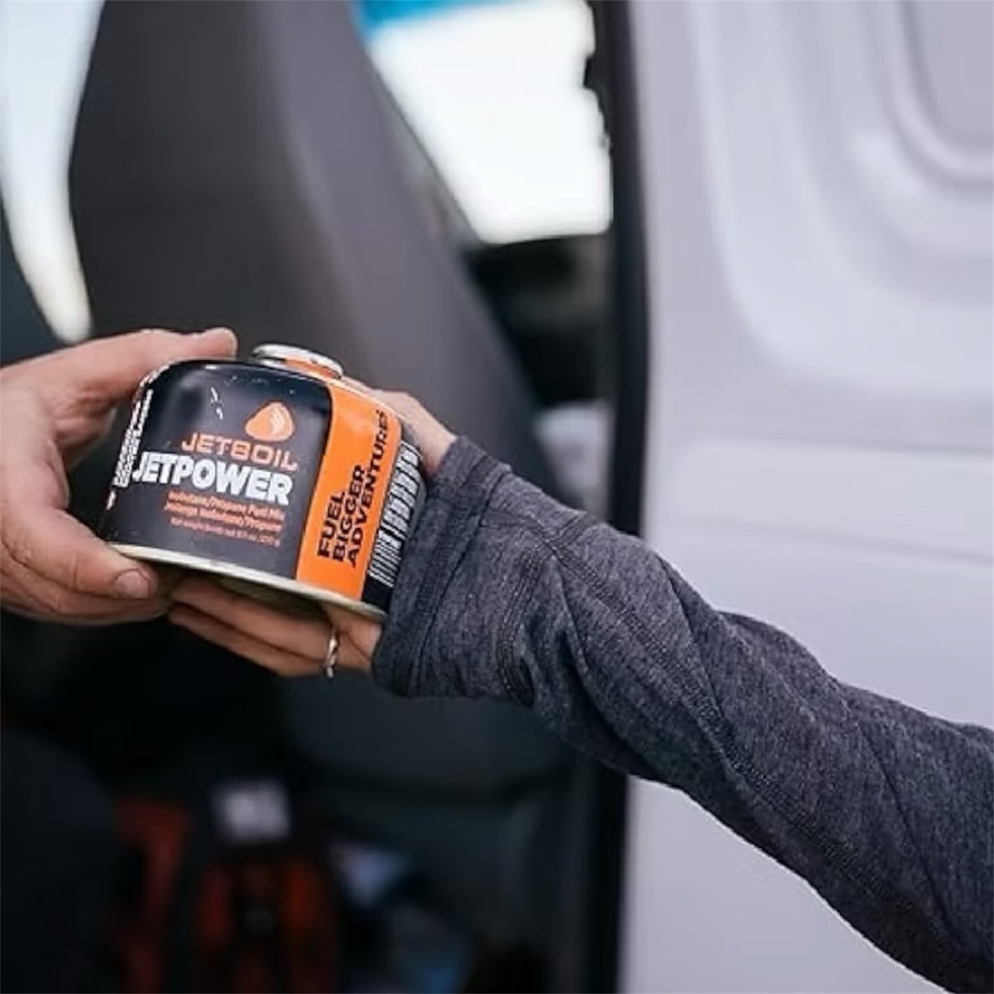 Person holding a Jetboil fuel canister with a blurred background