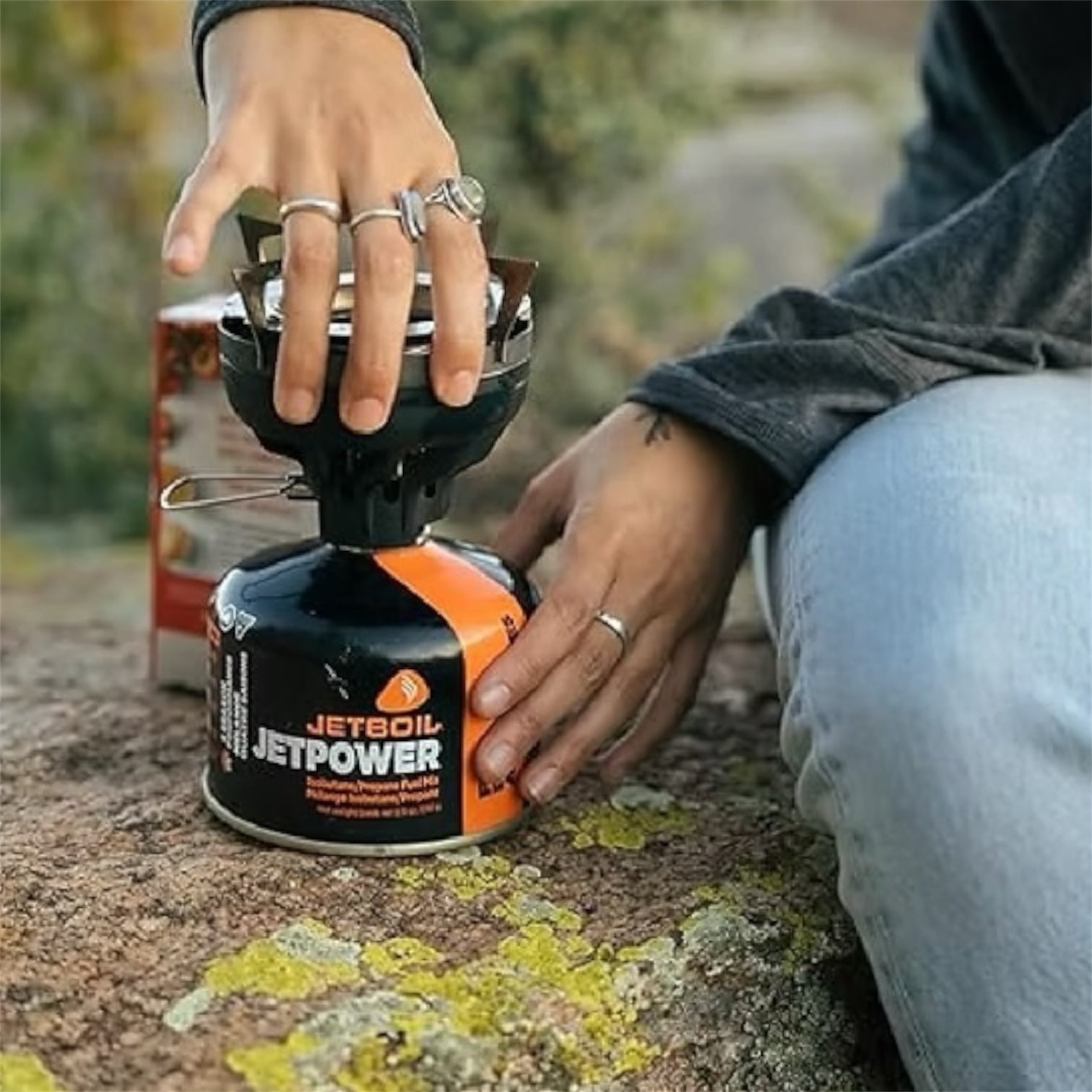 Person using a Jetboil stove with a visible 'Jetpower' canister outdoors.