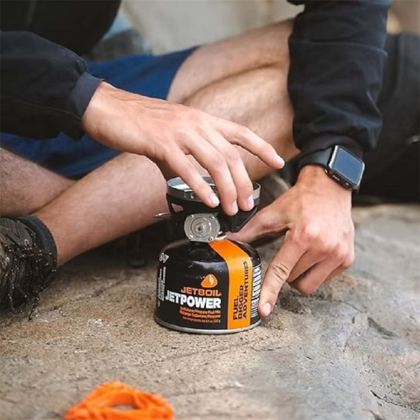 Person using a Jetboil stove on a rocky surface